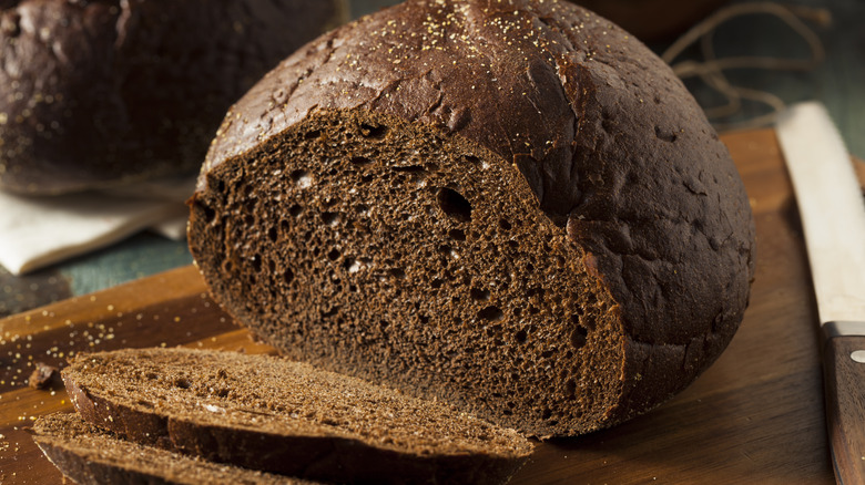 Pumpernickel loaf sliced on board