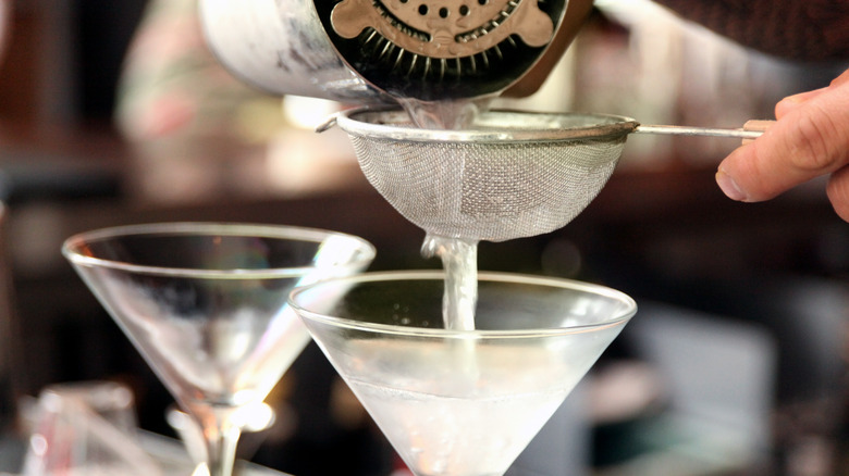 Person straining martinis