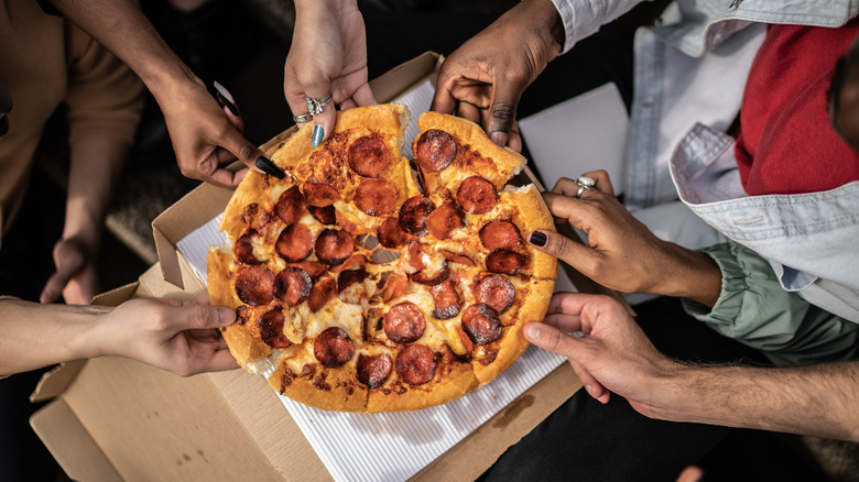 Hands grabbing slices of pizza