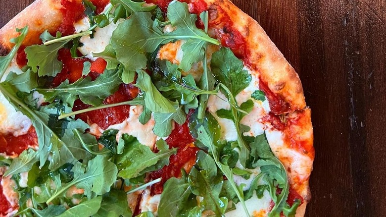 Pizza with arugula, tomato, cheese