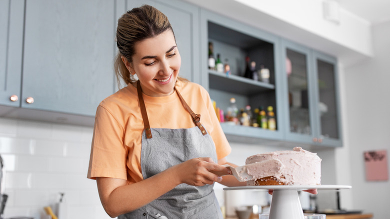 woman frosting cake in kitchen