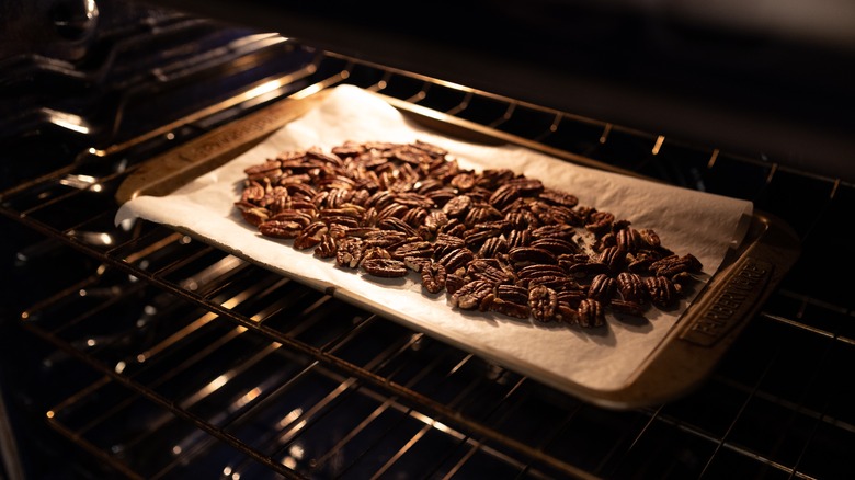 Roasting pecans in an oven on a baking sheet covered in parchment paper