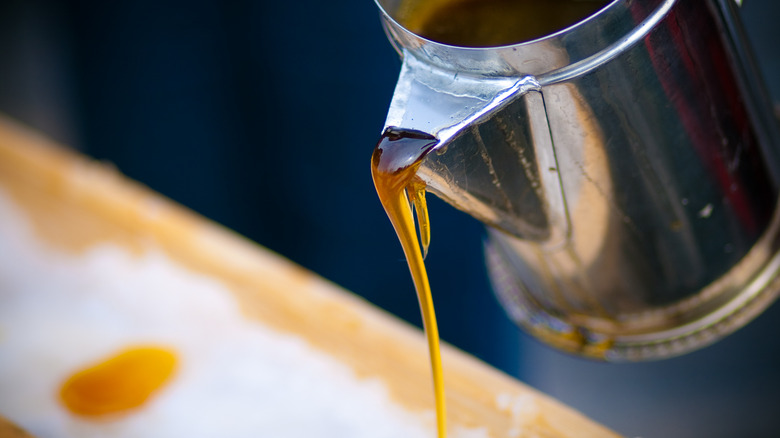 A close-up of golden maple syrup pouring from a metal dispenser