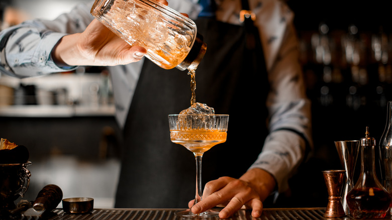 bartender pouring cocktail into glass