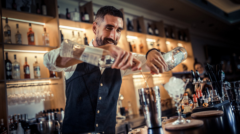 bartender pouring two bottles into shaker