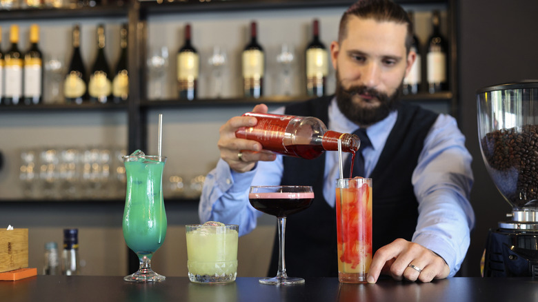 bartender pouring grenadine into cocktail