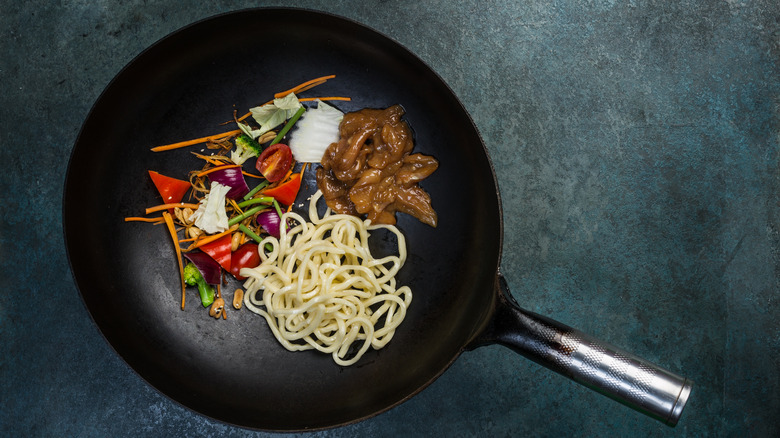 Stir fry ingredients in wok on black background