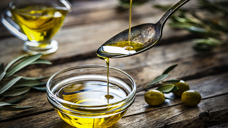 Olive oil on spoon dripping into bowl 