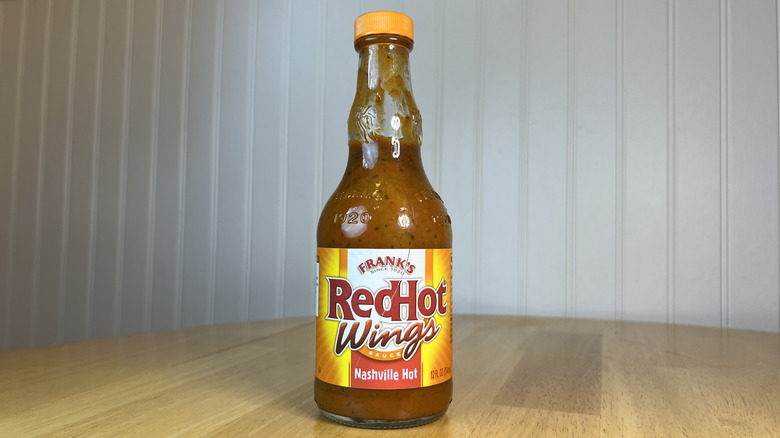 Bottle of Frank's RedHot Wings Nashville Hot Sauce on wooden table