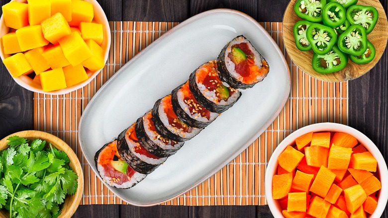 spicy tuna roll on a plate with bowls of mango cilantro jalapeno carrots