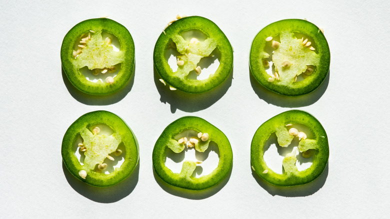 six slices of fresh raw jalapeno on white background