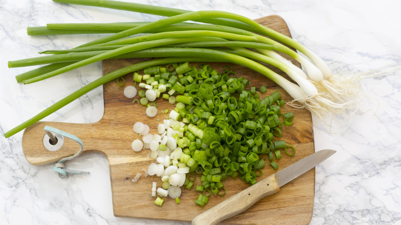 scallions chopped on a board with knife