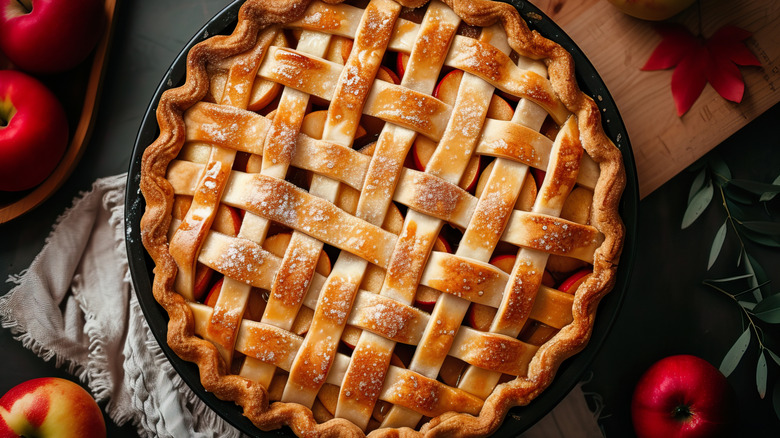 Latticed apple pie in pan with apples and cloth