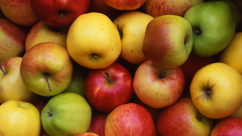 Green, yellow, and red apples as background