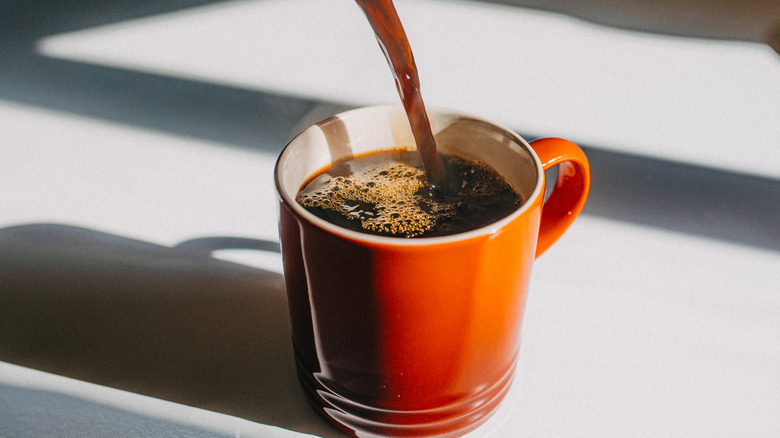 Coffee being poured into a red mug