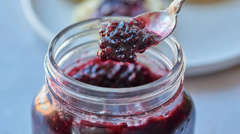 Person spooning vanilla blackberry jam from a jar