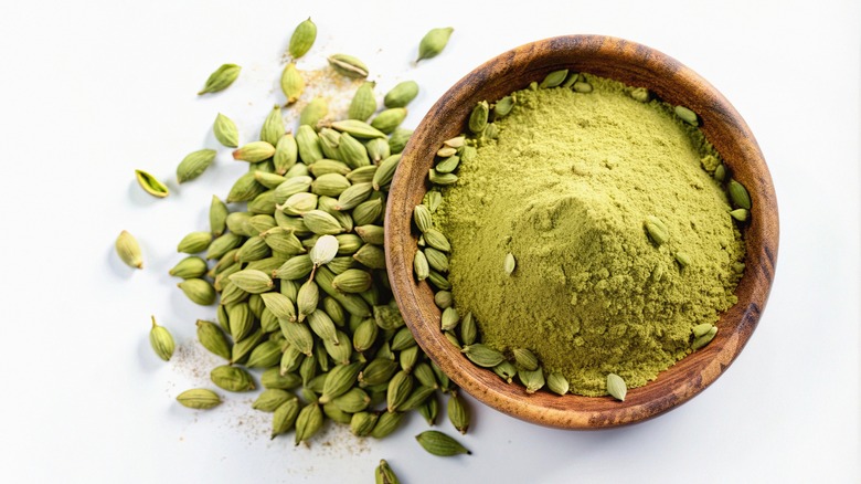 A wooden bowl filled with ground cardamom powder