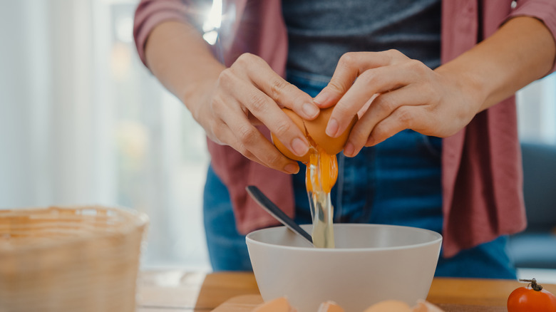 Cracking eggs into white bowl