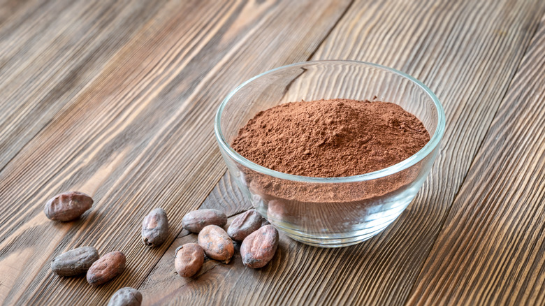 Cocoa powder in glass bowl with cacao beans