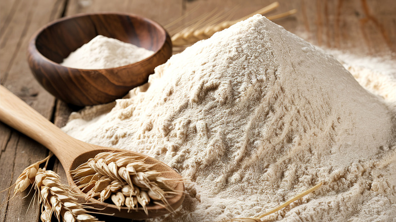 Whole wheat flour on surface next to wooden spoon