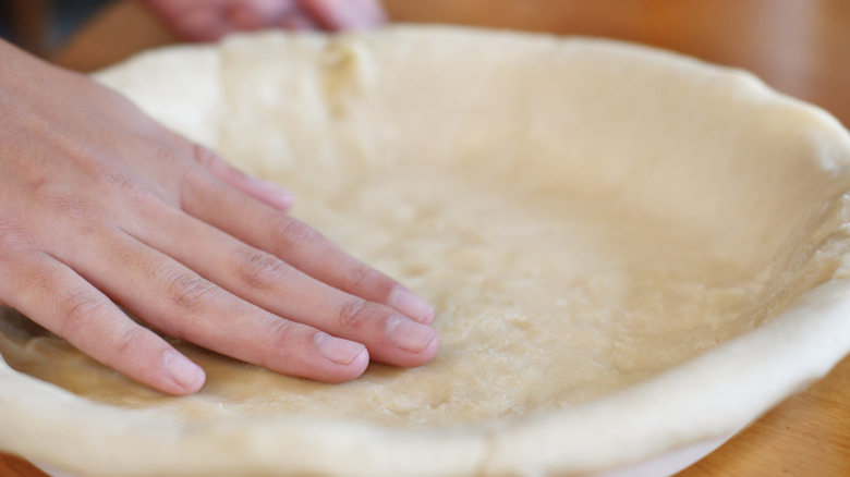 Pressing pie dough into tin