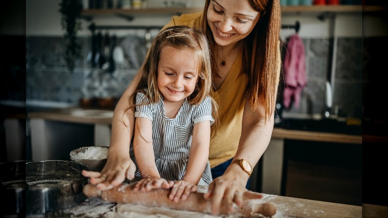 Child and parent rolling dough