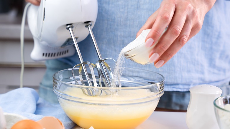 Pouring sugar into eggs with electric mixer