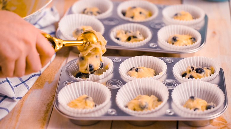 Scooping muffin batter into tins