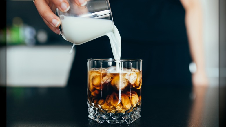 woman pouring milk into a drink