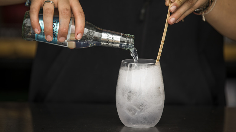 bartender pouring tonic into a drink