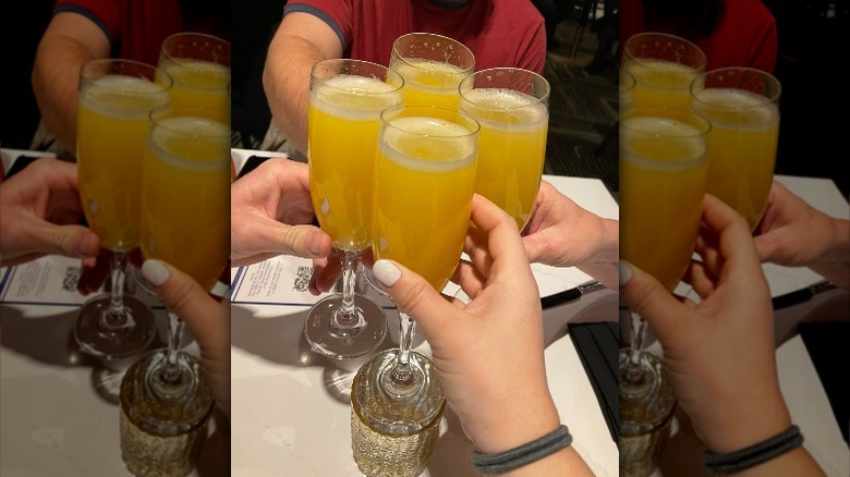 People toasting mimosa glasses