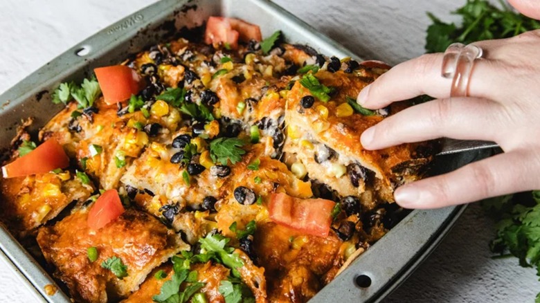 A person taking out a slice of corn and black bean Mexican casserole
