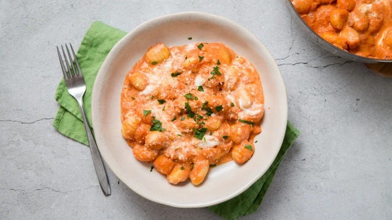Gnocchi alla vodka with burrata on a plate with a fork and napkin on the side