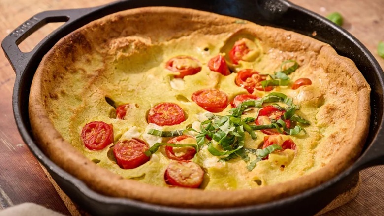 Caprese pesto Dutch baby in a cast iron skillet on a table