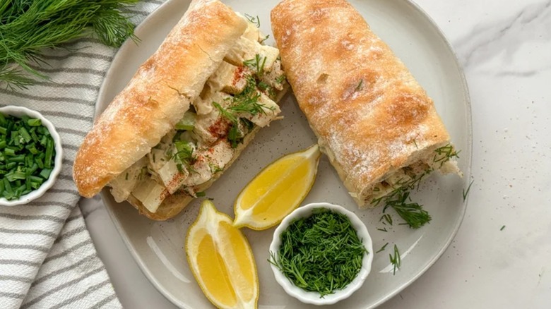 Top view of vegan hearts of palm lobster rolls on a plate with a wedge of lemon and dill garnish