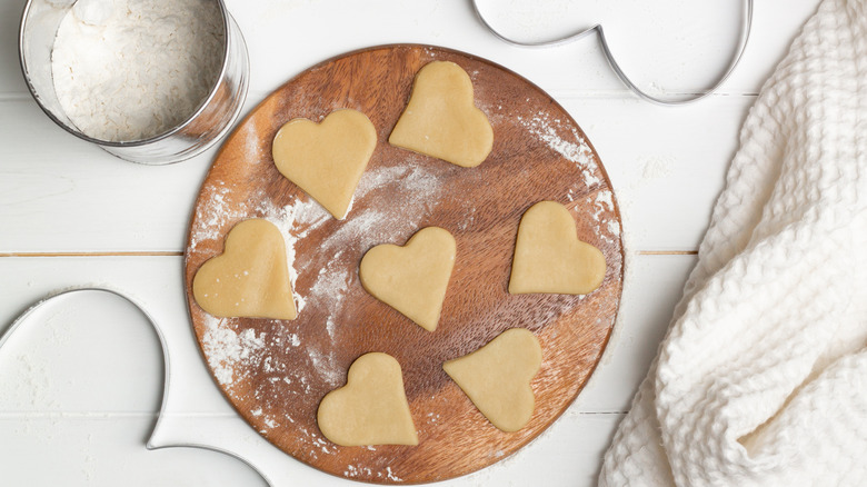 Heart-shaped dough cutouts on wooden board