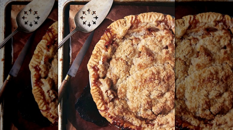 Cross-hatched apple pie on baking sheet with knife