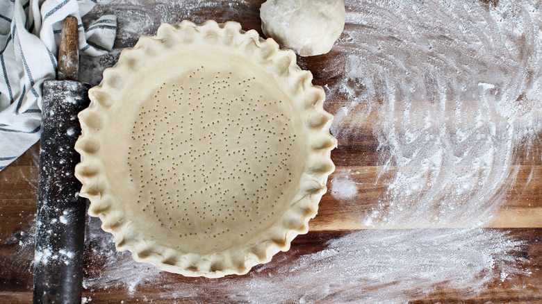 Scalloped edge pie crust in tin with rolling pin