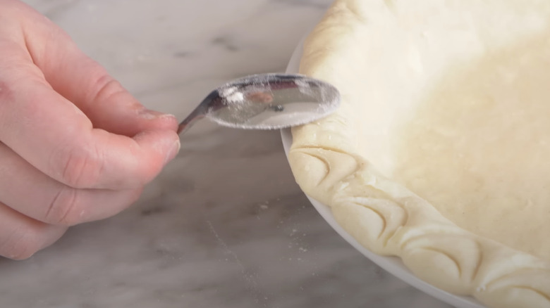 Stainless steel kitchen spoon pressed into pie dough