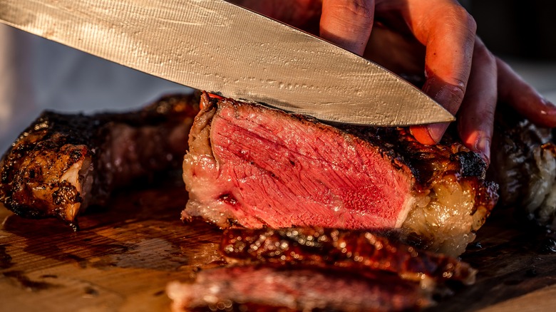 Knife slicing juicy steak