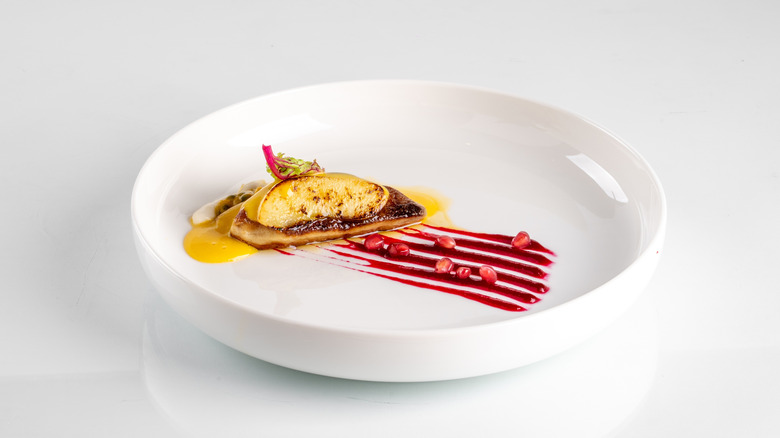 Elegant gourmet dish with artistic presentation of fine dining cuisine on a clean, white plate with vibrant sauce details.