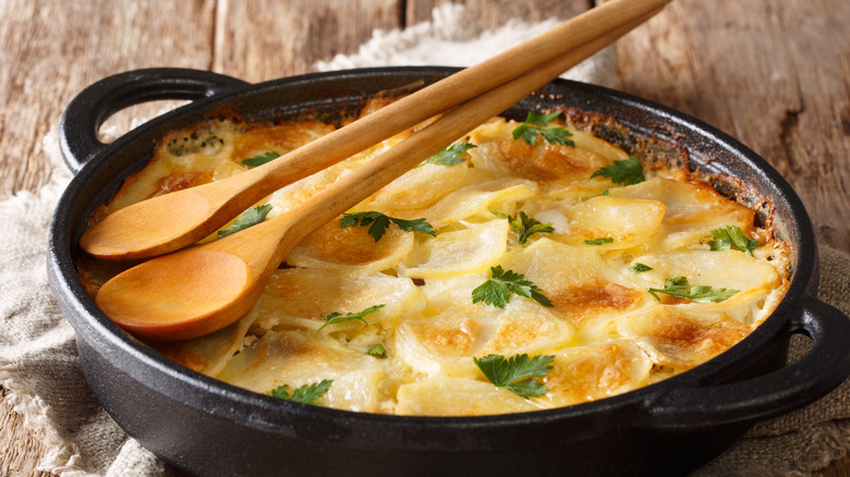 Sliced potatoes in with wooden spoon on top