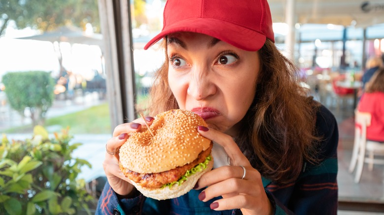 Woman sniffing burger suspiciously