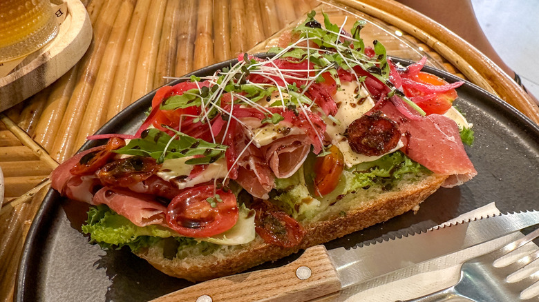 Open-faced whole wheat sandwich with Prosciutto ham, Brie cheese, sun-dried tomatoes