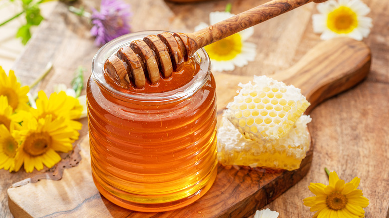 organic honey in glass jar, honey dipper and honeycombs