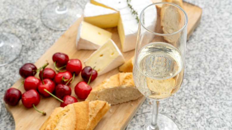 heeses, grapes, nuts and red wine on a gray background