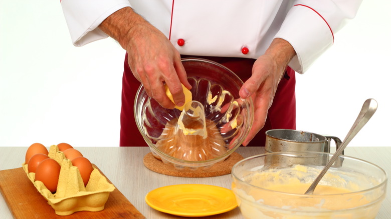 Hands greasing a Bundt tin with butter