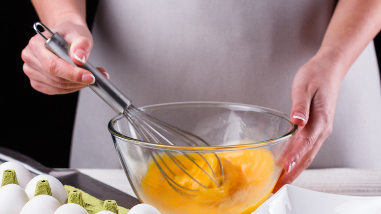 Person in apron whisking eggs