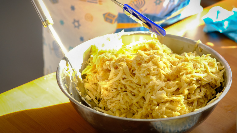 Mixing shredded potatoes in bowl