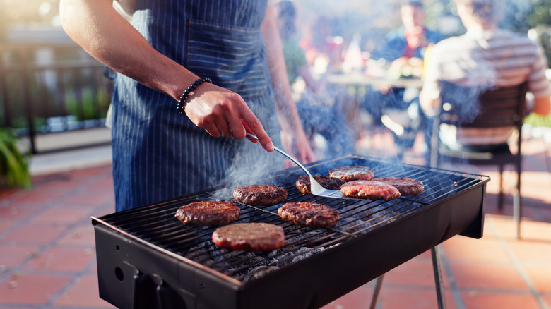 Person grilling burgers outside on a grill